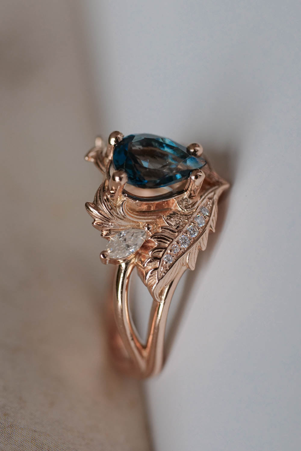 London blue topaz engagement ring in rose gold , pear cut topaz and marquise cut small diamonds or moissanites above ans details. 